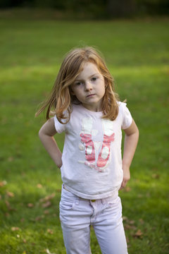 Young Ballerina. A rough and ready young girl, pulling her trousers up in an efficient manner has pretty ballerina feet on her t-shirt.