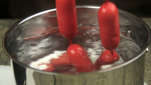 A string of Australian frankfurters called cheerios being lowered in a pot 