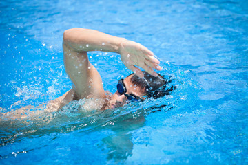 Young man swimming the front crawl in a pool