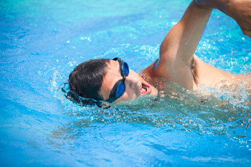 Young man swimming the front crawl in a pool