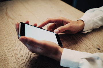 Smartphone holding in female hand on the wood table