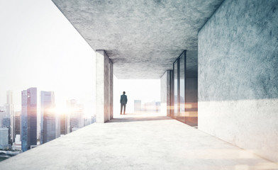 Young businessman standing on the edge of skyscraper and looking