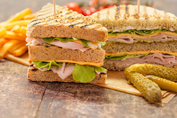 Club sandwich on wooden table with french fries