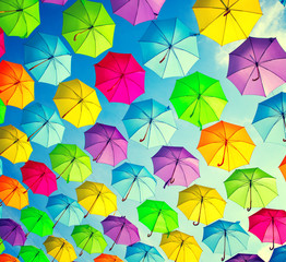 Hanging multicolored umbrellas over blue sky. Abstract background