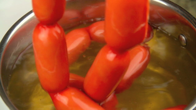 A string of Australian frankfurters called cheerios being lifted out of a pot 