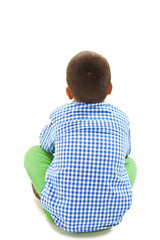 Rear view of little boy sitting on floor. Isolated on white background