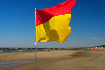Red and yellow flag on the beach of the Baltic Sea