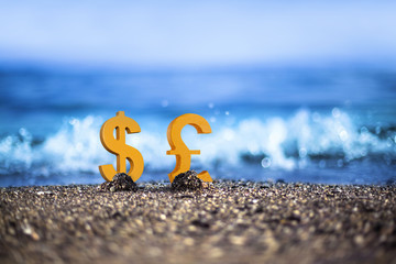 Dollar and Pound currency icons are standing on the wavy sea side