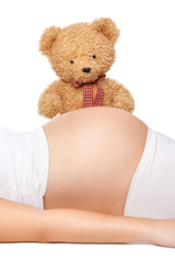 Teddy bear looking at belly of a pregnant woman