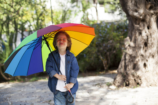 Lovely young boy with umbrella in garden