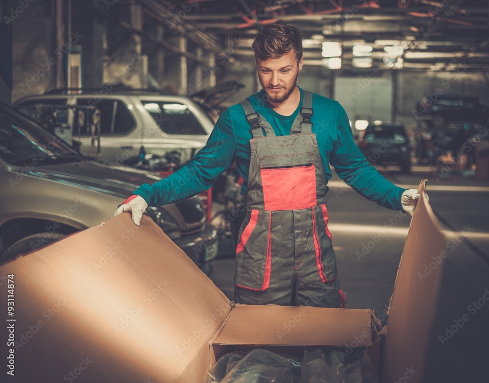 Sticker Mechanic opening box with new spare parts in a workshop