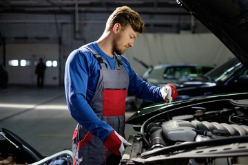 Mechanic checking oil level in a car workshop