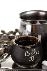 a Cup of coffee and spoon on the spacing next to the Turk for coffee on white isolated background