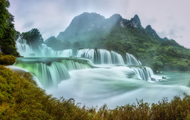 Ban Gioc Waterfall craggy limestone permissive side misty morning with foreground grass and tones...