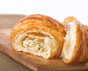 Flaky french croissant pulled apart on a board isolated