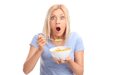 Shocked woman eating cereal from a bowl