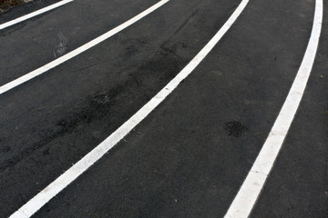 Fototapeta premium Running asphalt track with white painted lines.