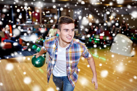 happy young man throwing ball in bowling club