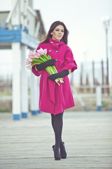 Fototapeta premium Beautiful woman are walking with a bouquet of tulips in a cities streets