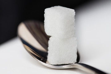 close up of white sugar cubes on teaspoon