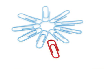 Blue paper clips in a circle with red paper clip outside.