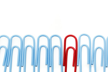 Blue paper clips in a row with one red one. Difference concept.