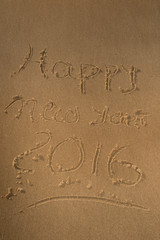 Happy new year 2016 written in the sand of sea beach.