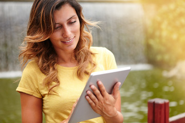 Fototapeta premium Young lady using tablet when standing by waterfall