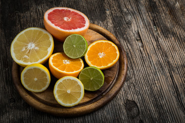 Naklejka na ściany i meble Halves of citrus fruits on wooden background. Orange, grapefruit