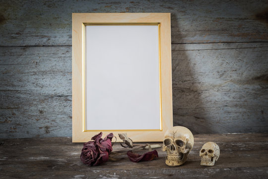 Still life skull, roses and Vintage photo frame on wooden background