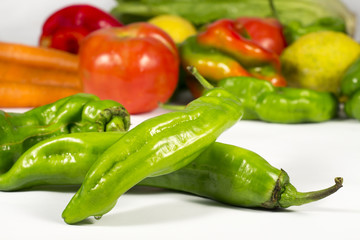 Green peppers in front of a bunch of vegetables and fruits