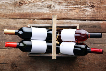 Wine bottles in basket on wooden background