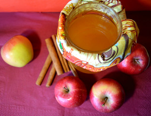Honey jar, apples and cinnamon sticks on a purple surface