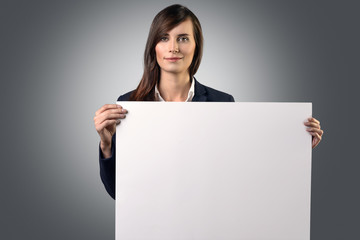 Fototapeta premium Attraktive Geschäftsfrau hält ein weißes Plakat oder Schild