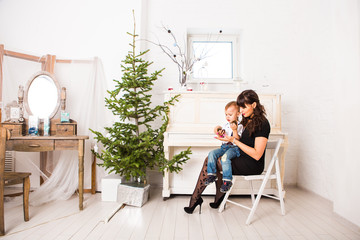 mother and  her son playing near an decorated fir-tree for