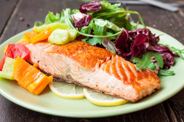 Fried salmon with vegetables on a wooden table
