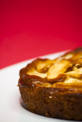 Apple pie on a white plate with red background