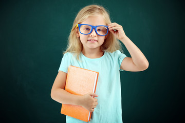 Beautiful little girl with book,  on blackboard background