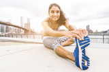 young woman making stretching in New york city. Brooklyn bridge and skyline in the background