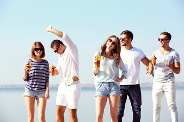 Young people with beer on the riverside