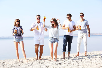 Young people with beer on the riverside