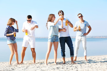 Young people with beer on the riverside