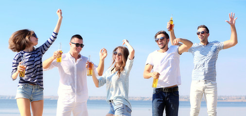 Obraz premium Young people with beer on the riverside