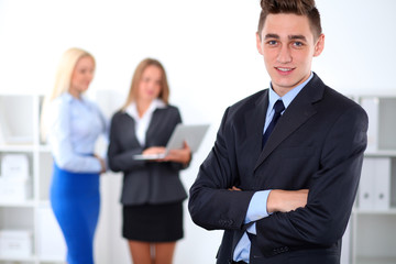 Fototapeta premium Cheerful business man in office with colleagues in the background, sturt-up team