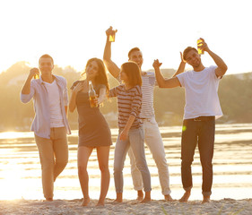 Obraz premium Young people with beer on the riverside