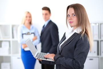 Obraz premium Pretty businesswoman in office with colleagues in the background