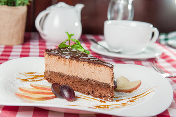 Close up Chocolate Cheesecake with fruits and  Green Mint on the white plate on the served  restaurant table 