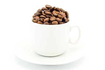 cup on a saucer filled with coffee beans isolated on white background
