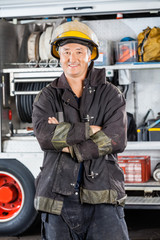 Mature Firefighter Standing Arms Crossed Against Firetruck
