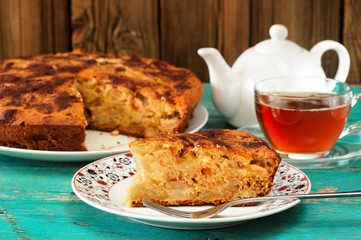Homemade yummy apple pie, black tea and white teapot on turquois